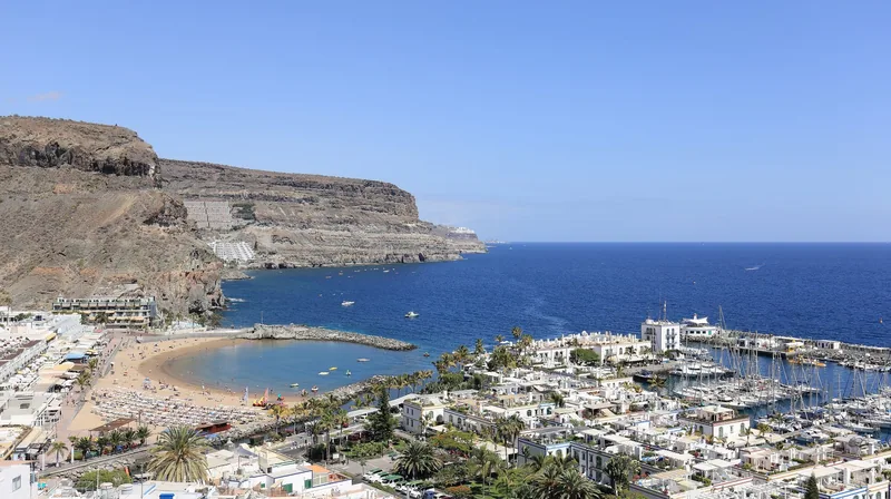 Panorama över Puerto de Mogán med strand, hamn och klippor