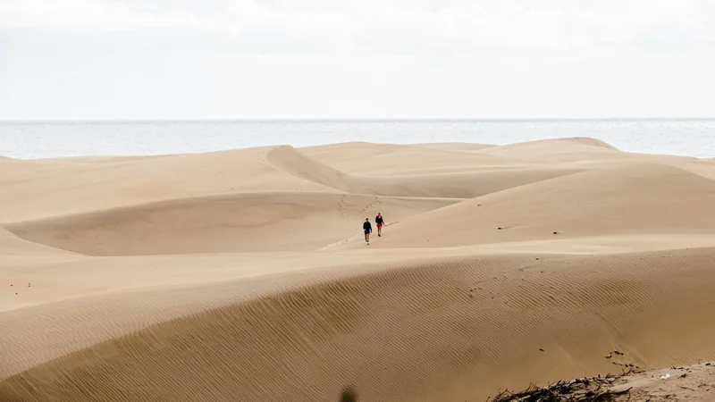 Två personer går ut över de vidsträckta sanddynerna i Maspalomas